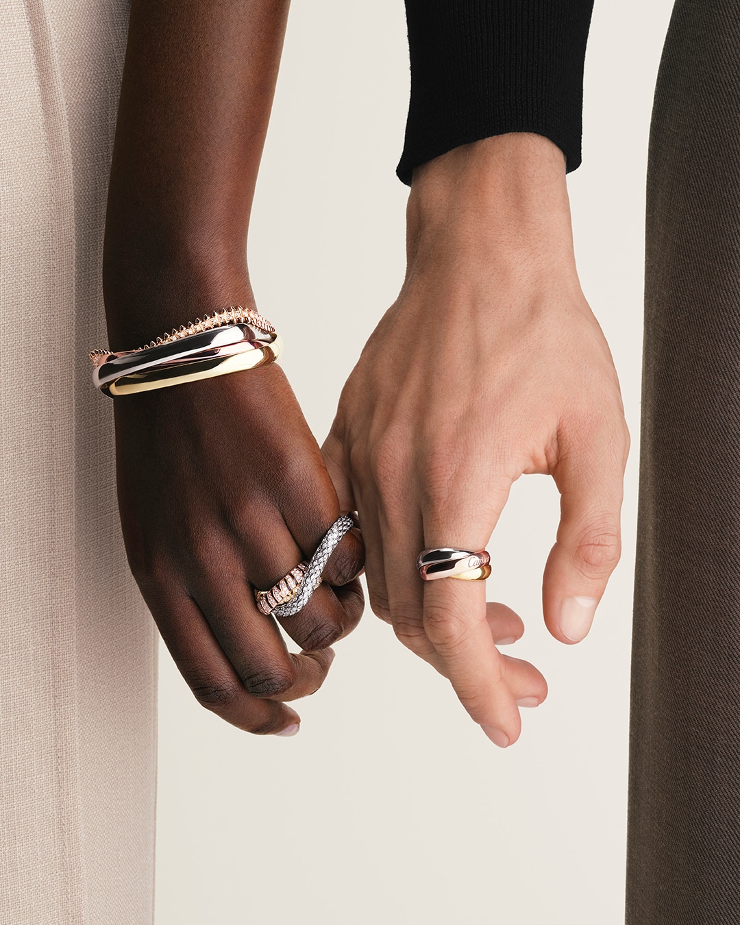 Cartier Trinity rings and bracelets stacked and worn on the hands
