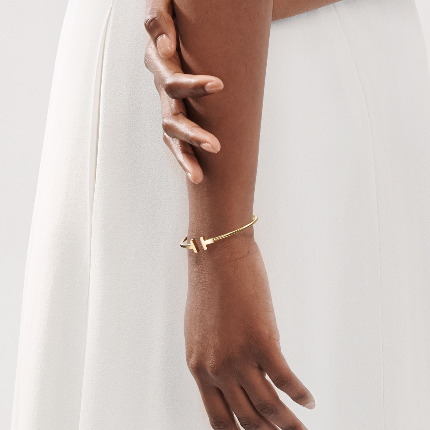 A lady wearing a Tiffany T Wire bracelet in gold