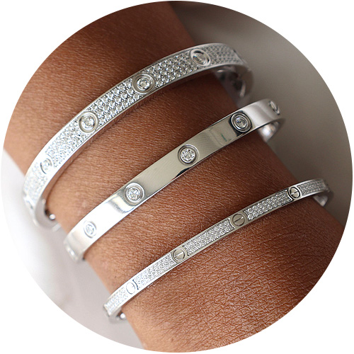 Three Cartier Love bracelets stacked on a lady’s wrist, plain gold and pavé diamond